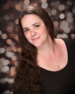 Person with long brown hair and light skin wearing a scoop neck black shirt with sparkle background