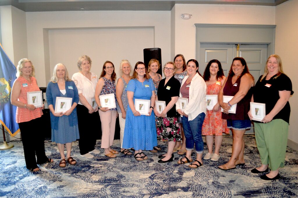 A line of women holding plaques in a ballroom